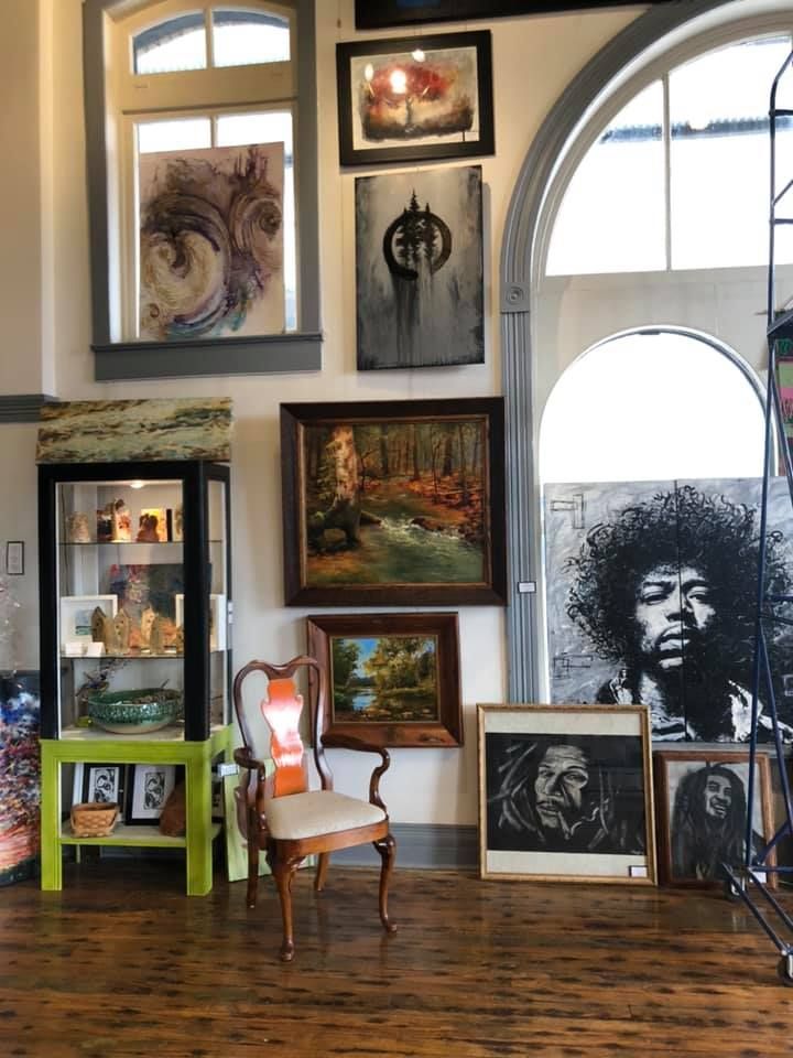 Art gallery interior with paintings, sculptures, and a display case. A variety of art styles, colors, and sizes.