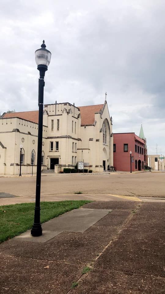 Street view of a church and other buildings on a cloudy day, with a lamppost in the foreground.