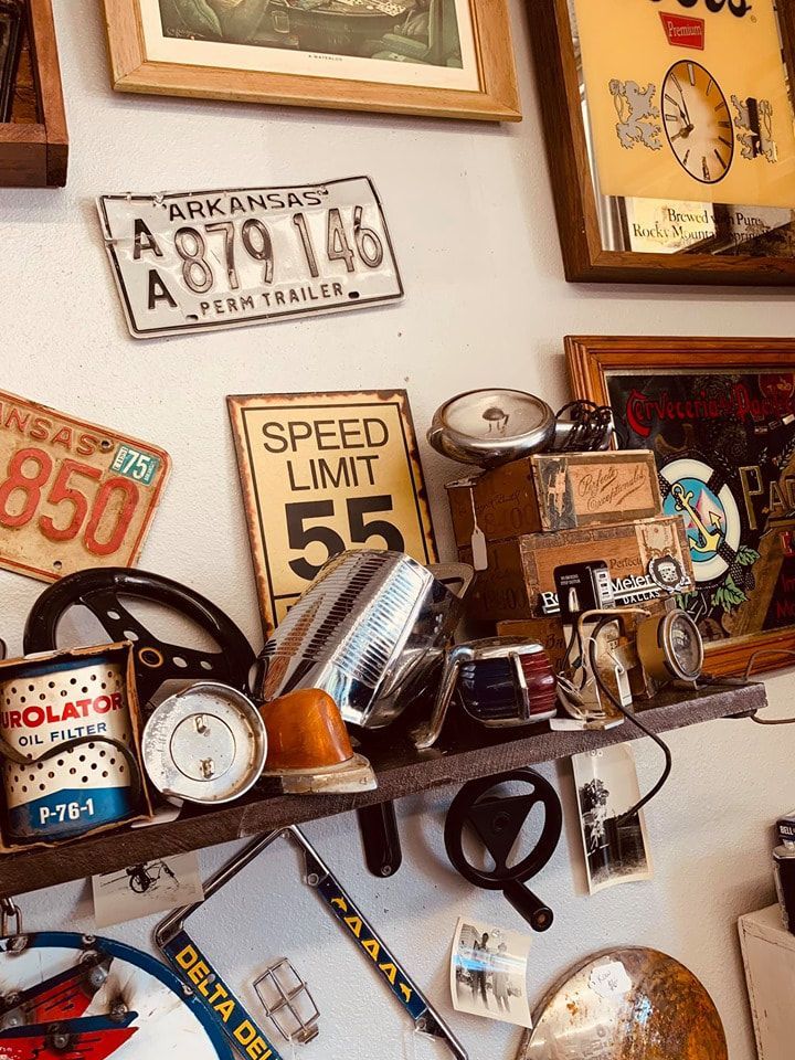 Vintage car parts and signs displayed on a shelf, including license plates and speed limit sign.