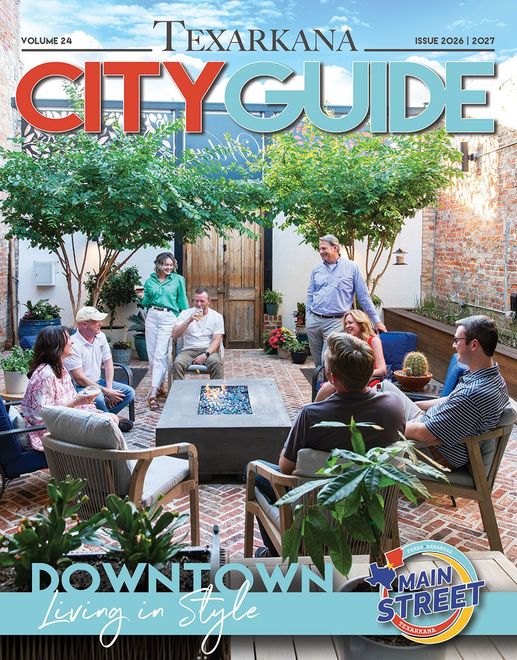 Texarkana City Guide cover: Two women smile, dine at a restaurant, holding drinks and food on a marble table.