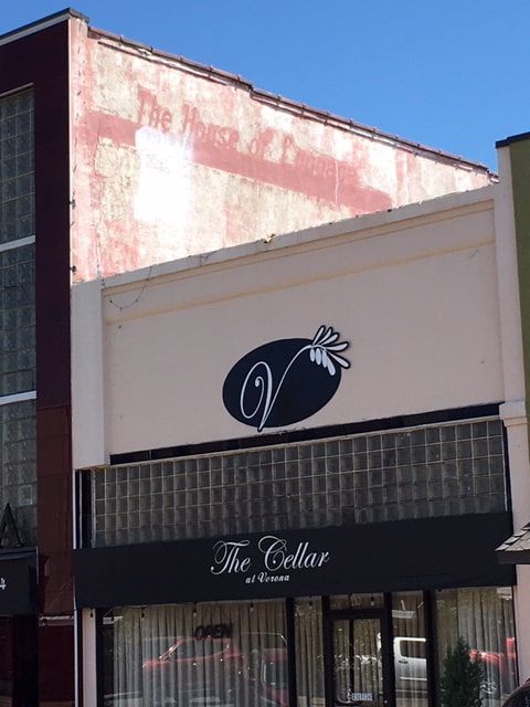The Cellar restaurant exterior with black awning, oval logo, and open windows.