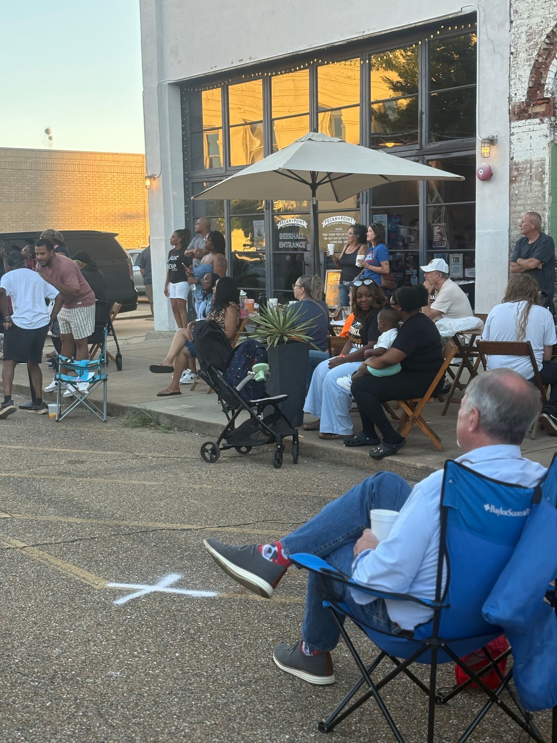 People gathered outdoors at a restaurant with an umbrella. 
