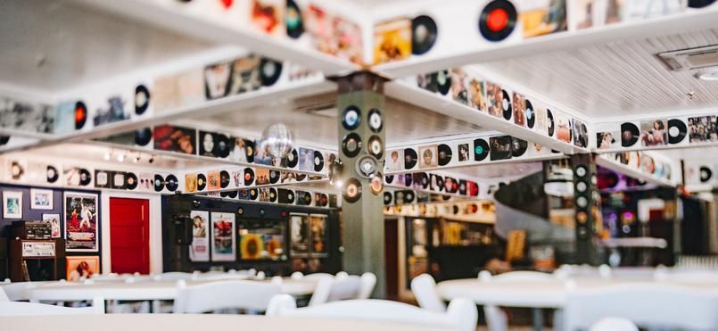 Restaurant interior decorated with vinyl records and album covers. White tables and chairs.