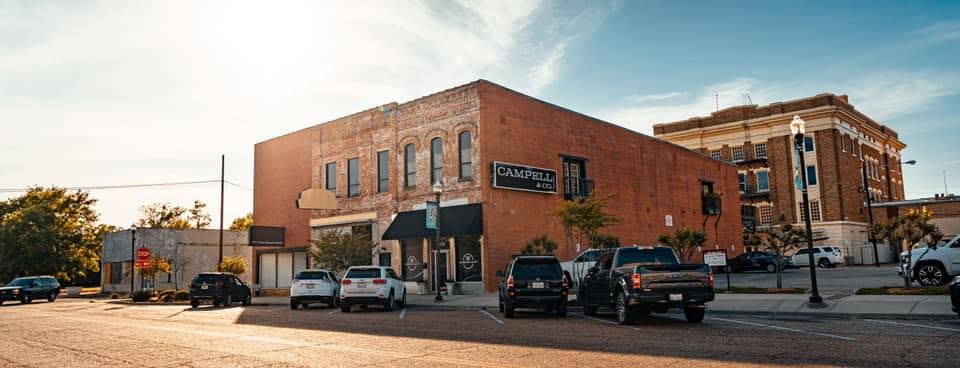 Buildings with parked cars on a street in a city. Bright sunlight.
