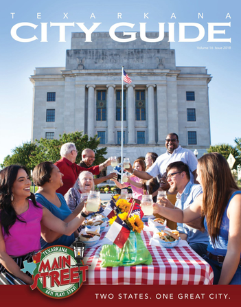 Texarkana City Guide cover: People toasting at an outdoor picnic with a large building 