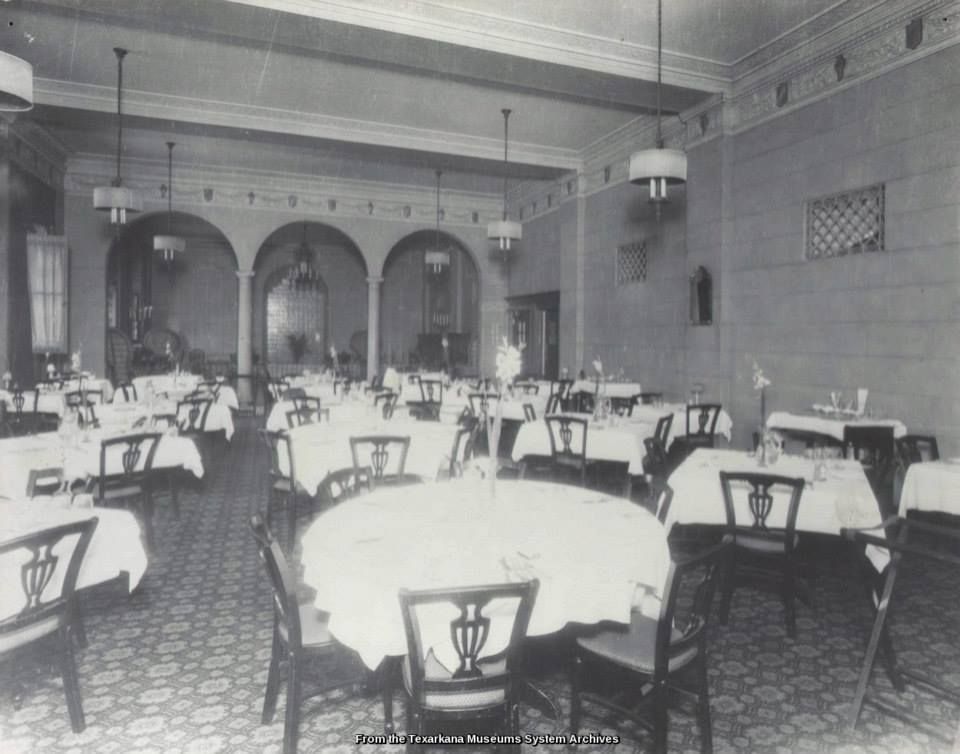 Formal dining room with white tablecloths, dark chairs, and arched alcoves.