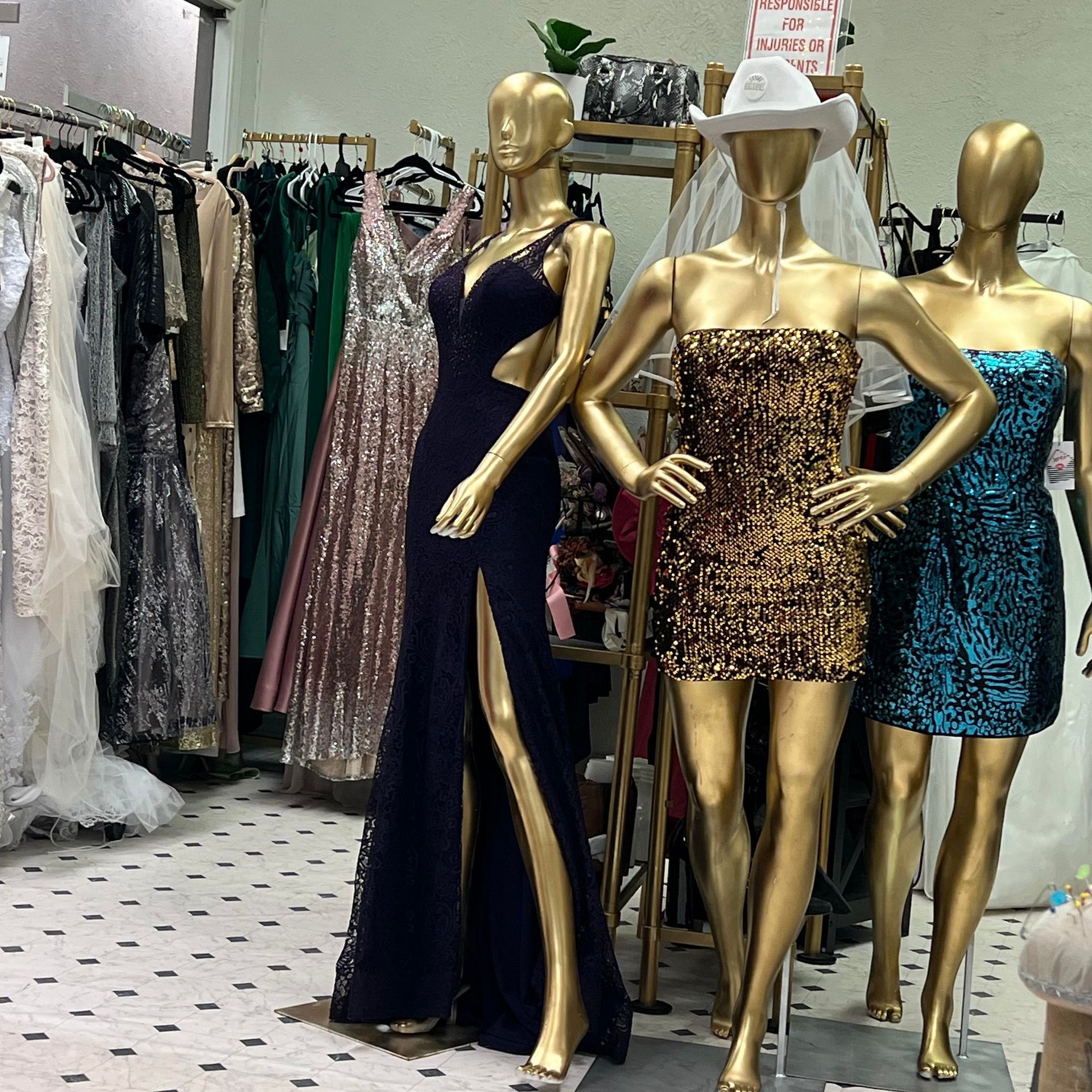 Inside a dress shop: Mannequins in evening dresses stand near racks of gowns.