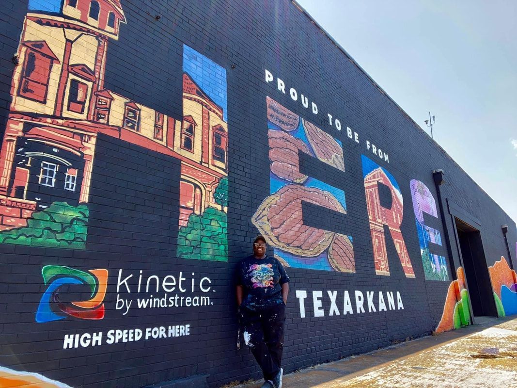 Person stands next to a Texarkana mural that says