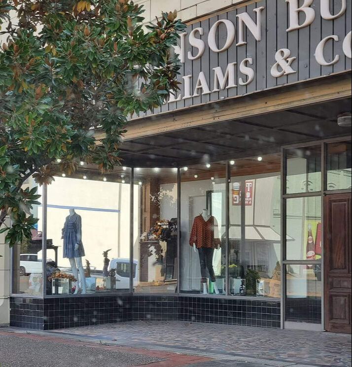 Storefront with mannequins in window display under a sign that reads