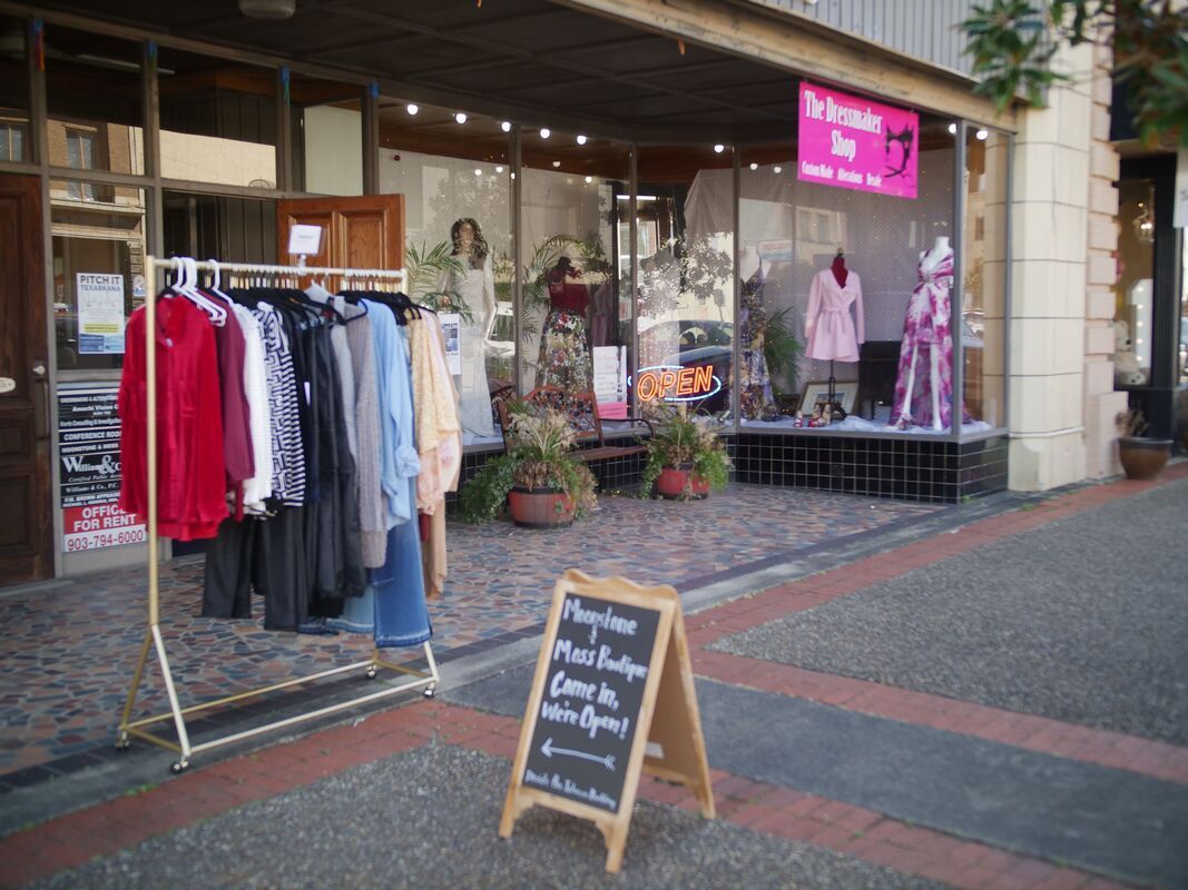 Clothing rack outside a boutique, with clothes on display. Sign reads 