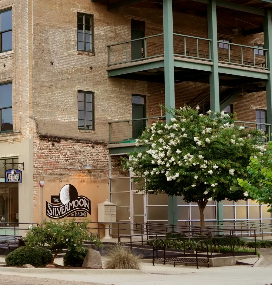Brick building with a balcony, Silvermoon sign, and flowering tree in front.