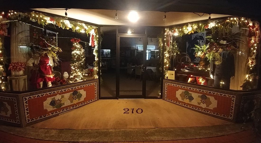 Storefront entrance decorated with Christmas lights and ornaments. The number 