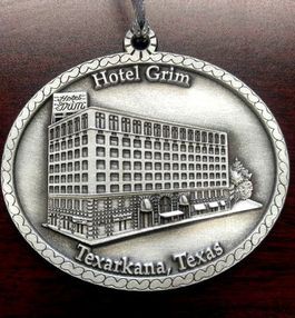 Ornament of the Hotel Grim in Texarkana, Texas. Gray metal with building illustration and text.