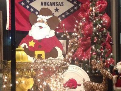 Christmas display with Arkansas flag background, Santa cutout, decorated tree, and reindeer.
