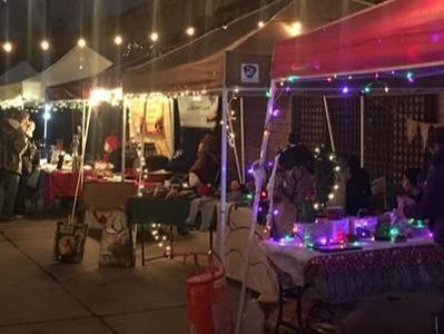 Night market with stalls lit by string lights; people browsing and shopping.