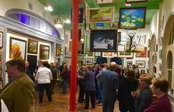 Art gallery interior with people viewing artwork on the walls. Red pillar. Green ceiling.