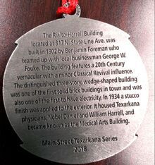 Medal with text describing the Rialto-Harrell Building in Texarkana, built in 1902.