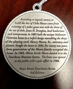 Metal medallion with text about the Ace of Clubs House in Texarkana, built in 1885.