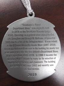 Ornament with text about Texarkana's first Dillard's Department Store. Dates and history engraved on the silver disc.