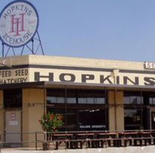Hopkins Icehouse restaurant exterior with brown building, large sign, and outdoor seating.