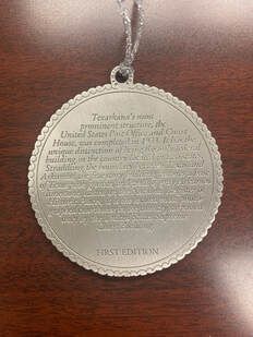 Silver circular ornament with text;