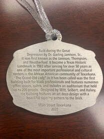 Silver ornament with text about the Grand Old Lady building in Texarkana, built during the Depression.