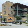 Multi-story brick building with metal balconies, mural, and street view.
