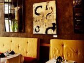 Restaurant interior with yellow booth seating, artwork, and tables set for dining.