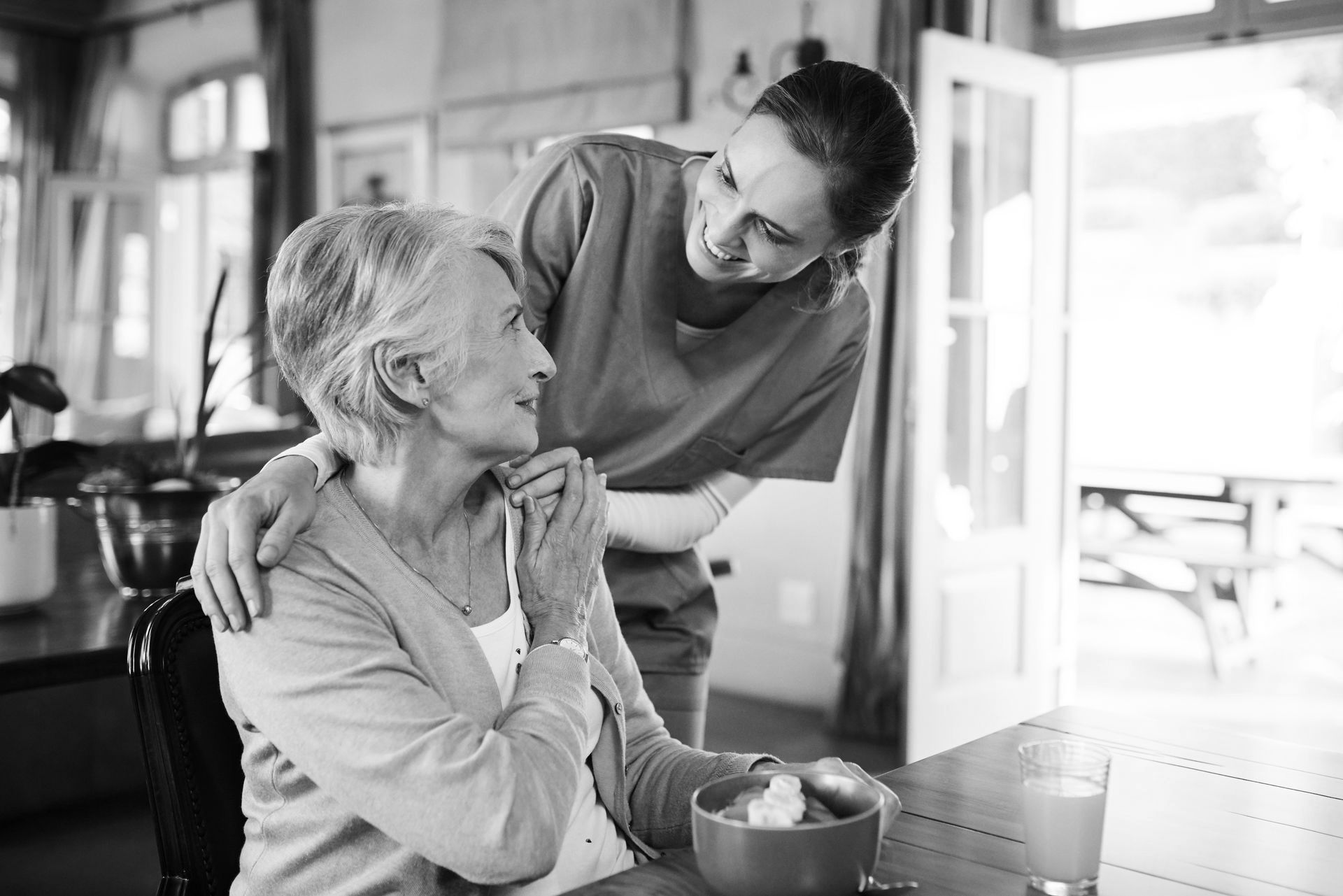Healthcare, elderly woman with nurse with breakfast at her home and at the table in living room. 