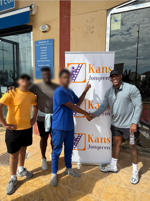 4 mannen voor een gebouw met een banner van Kans Jongeren