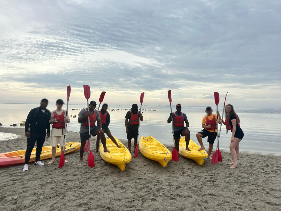 Jongeren poseren naast gele kayaks