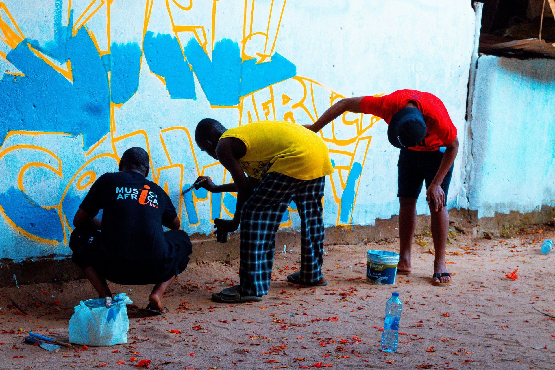3 mannen die blauwe graffiti aan het spuiten zijn op een muur