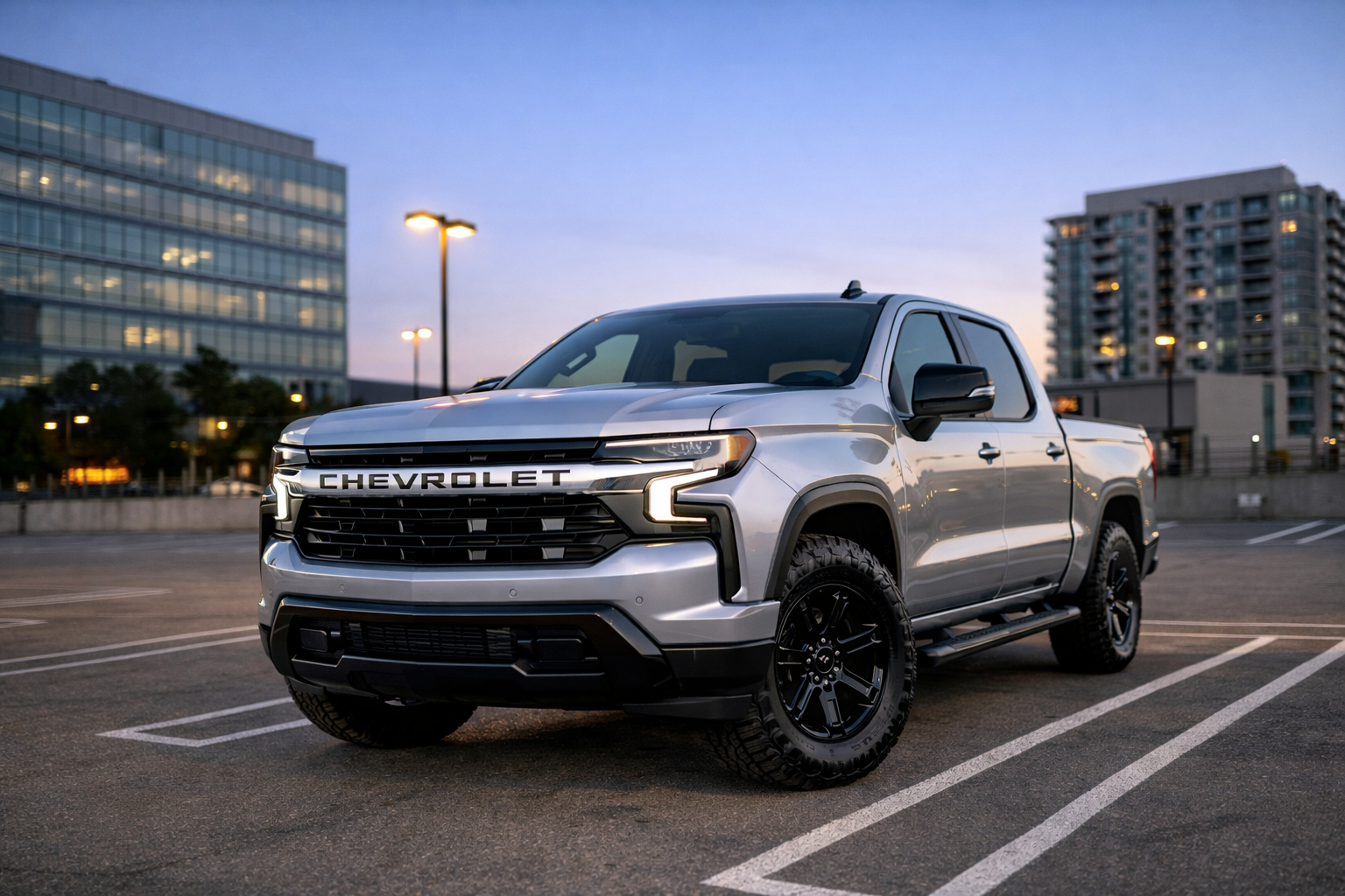 Silver Chevrolet Silverado EV pickup truck parked in a city lot at dusk.