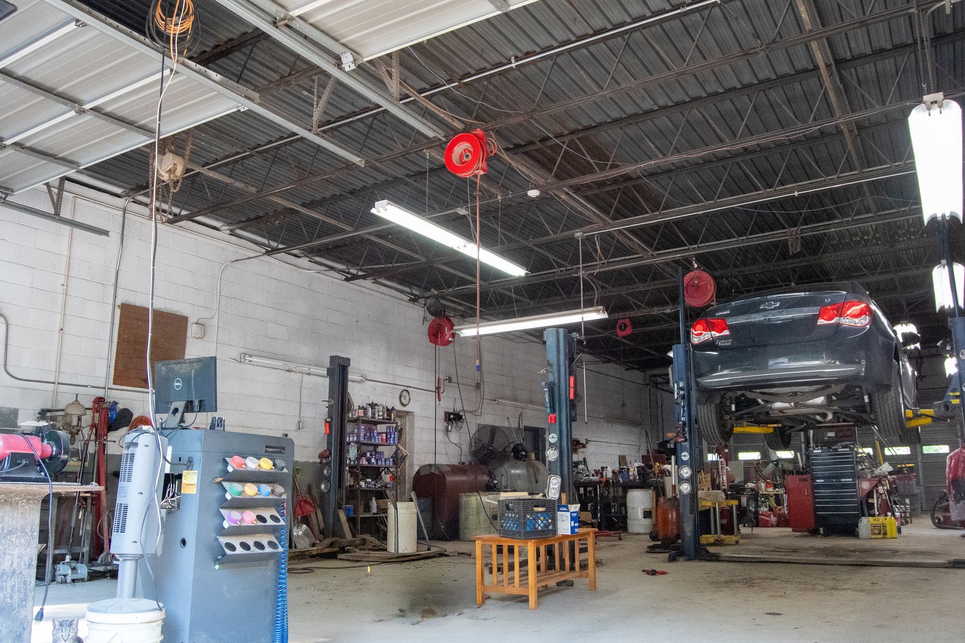 The interior of the auto repair shop at S&S Automotive Service shows a car elevated on a hydraulic lift, diagnostic equipment, and tools.