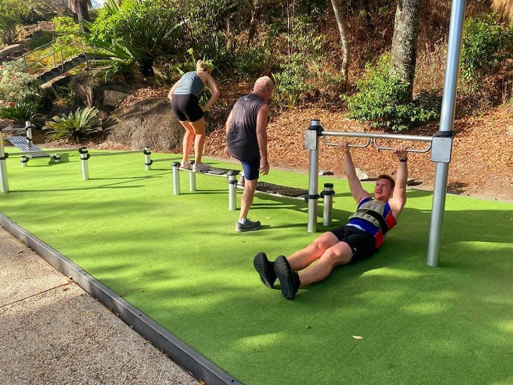 A Man Is Doing Push Ups On A Bar While A Woman Watches — Maxenergy Fitness In Smithfield, QLD