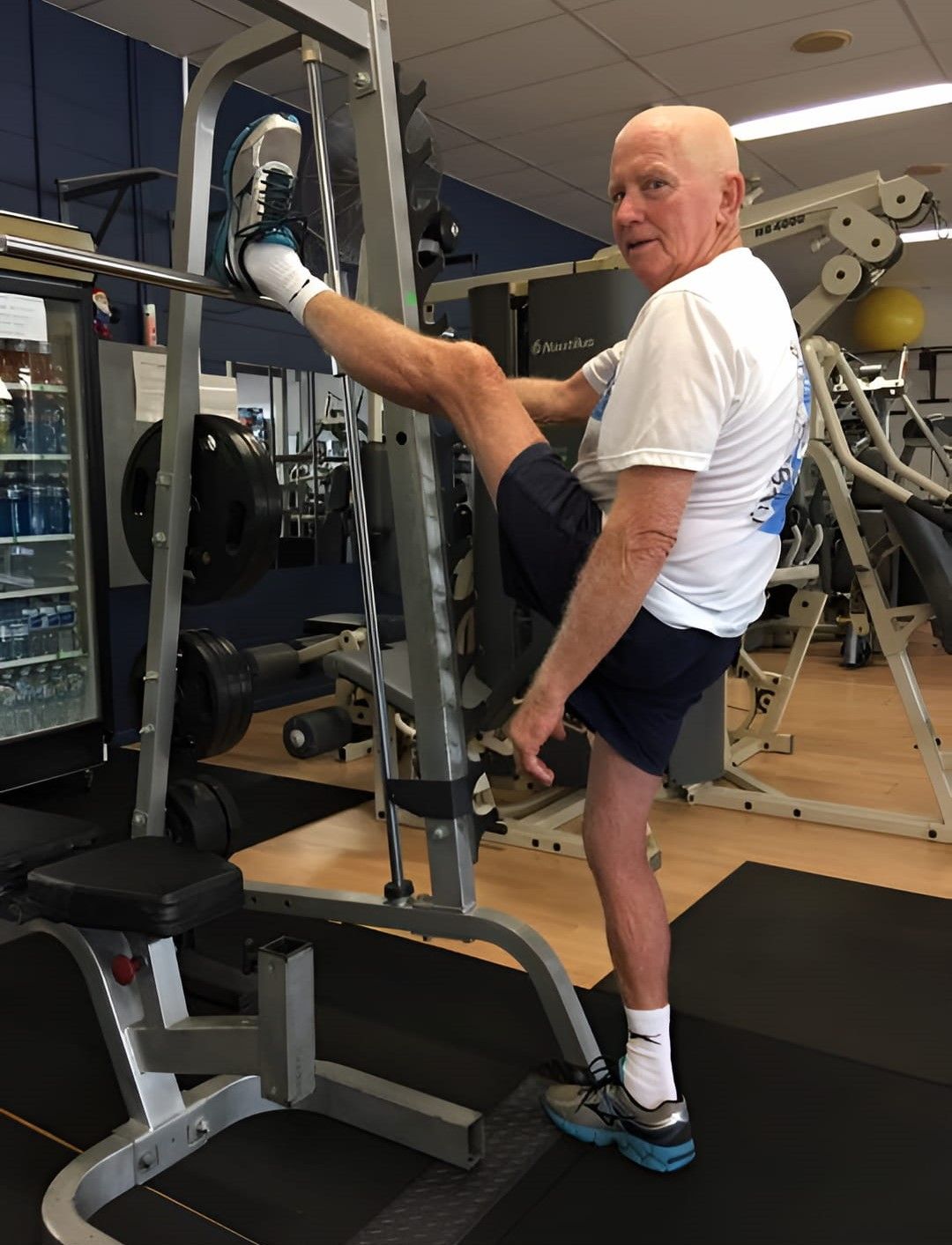 An Elderly Man Is Stretching His Leg On A Machine In A Gym — Maxenergy Fitness In Smithfield, QLD