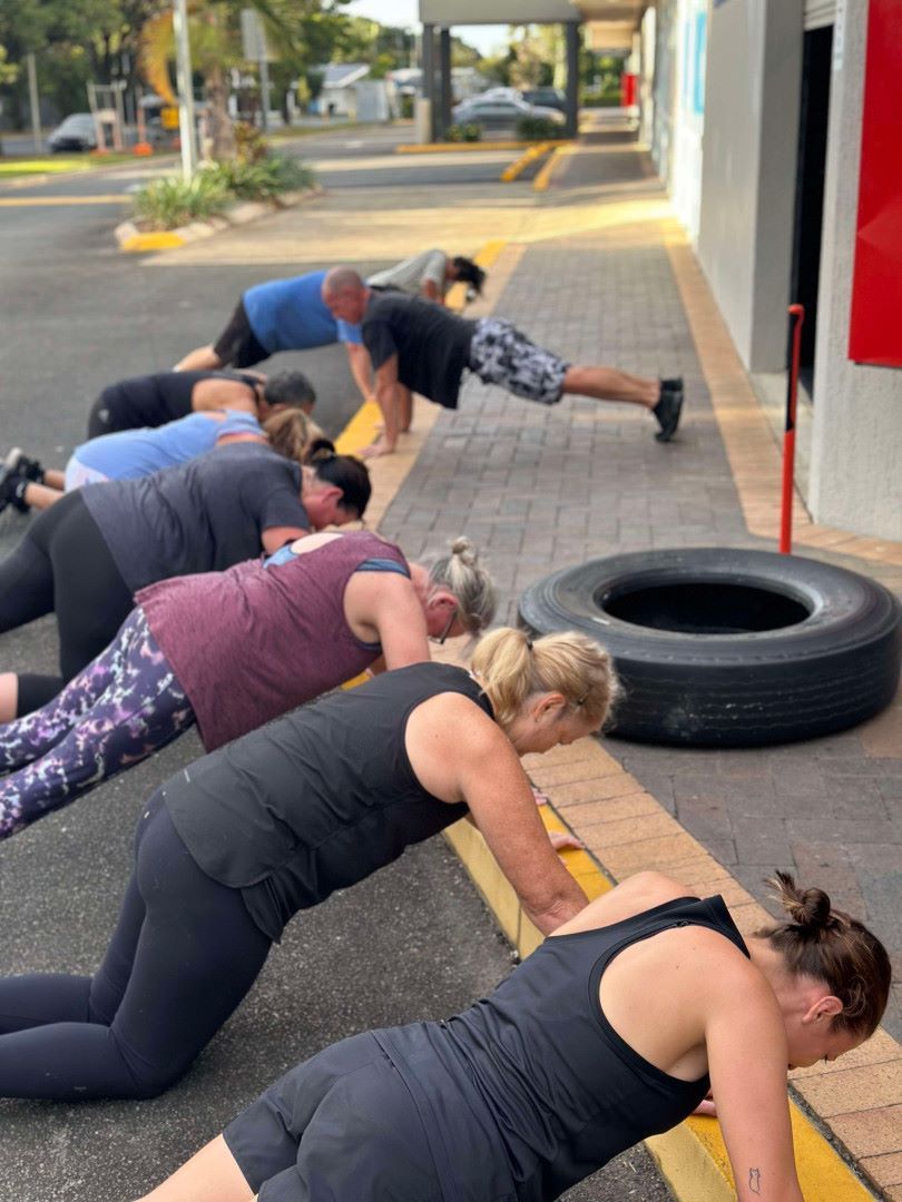 A Group of People Are Doing Push Ups on the Side of the Road — Maxenergy Fitness in Smithfield, QLD