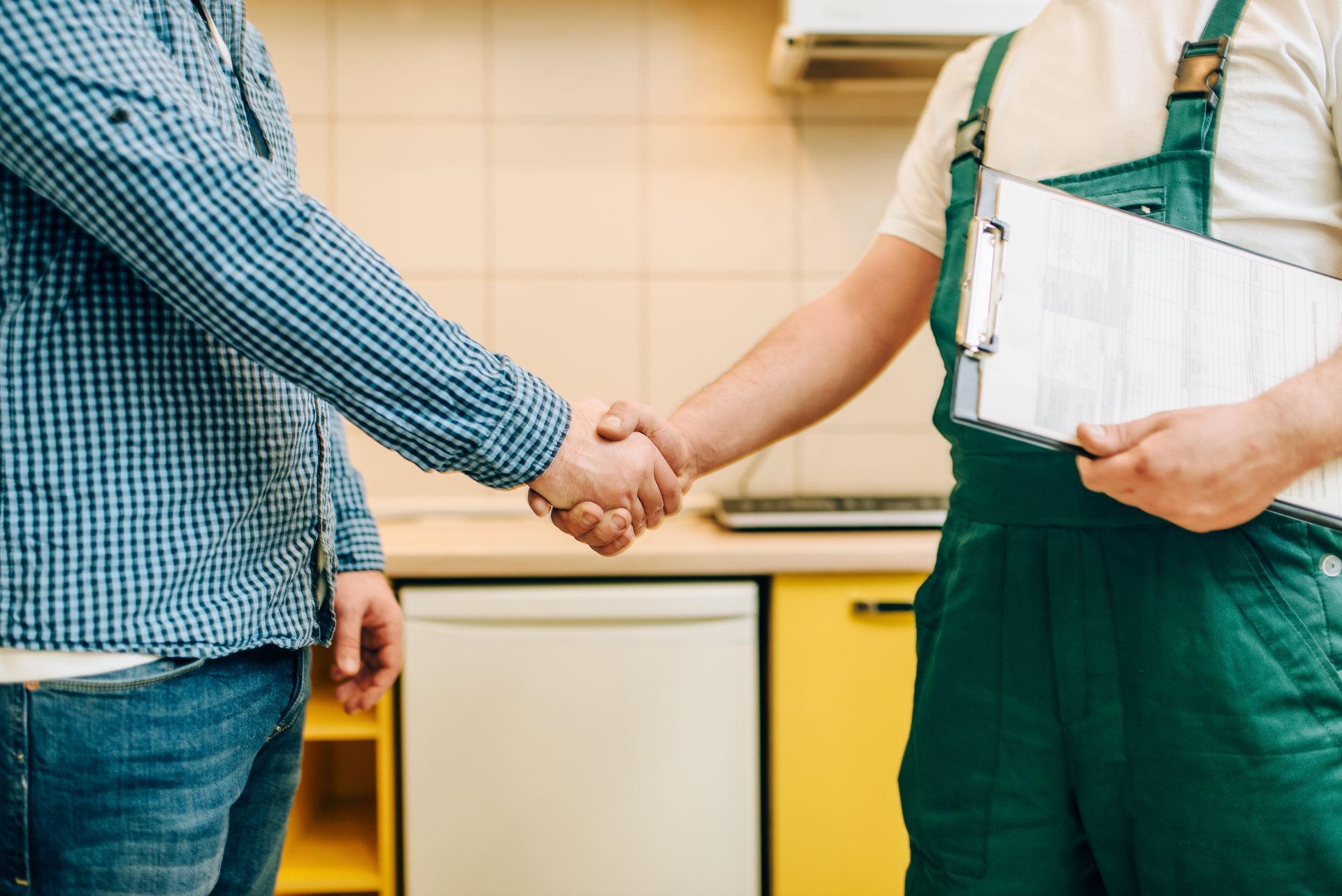 A plumber is inspecting the pipes under a kitchen sink. A plumber is inspecting the pipes under a kitchen sink.