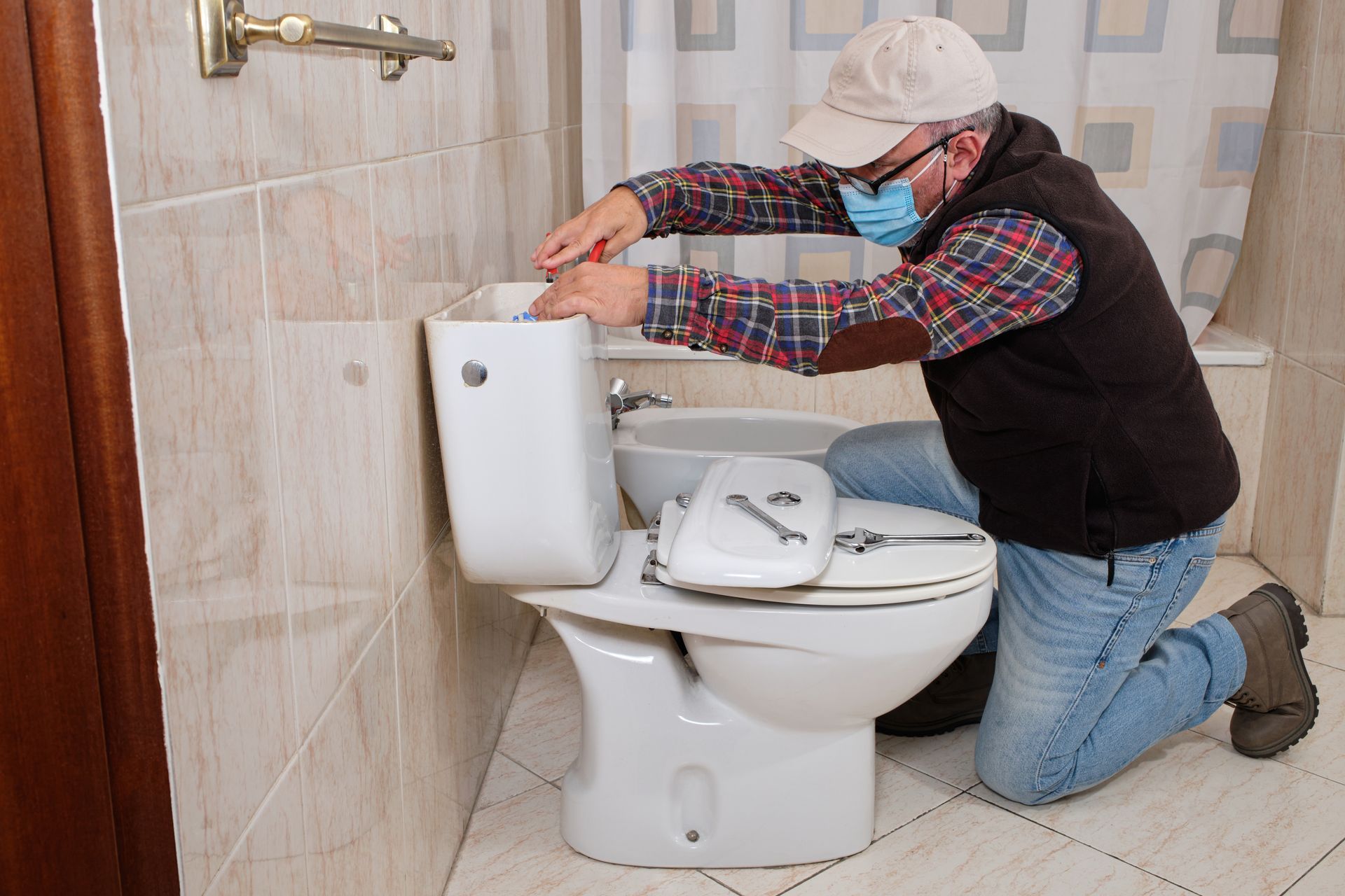 Residential plumbing repair technician fixing toilet tank components in home bathroom.