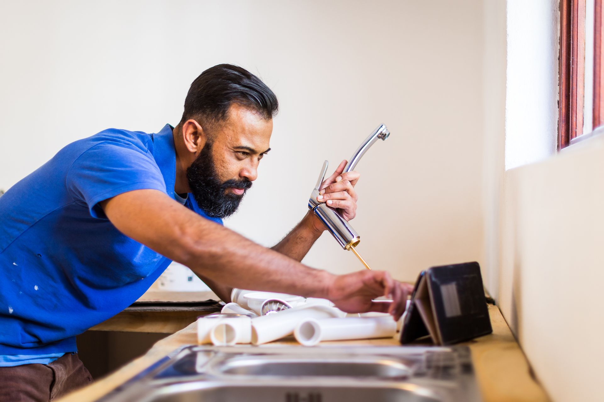 Plumber fitting tap in kitchen, showcasing his expertise in residential plumbing installation.