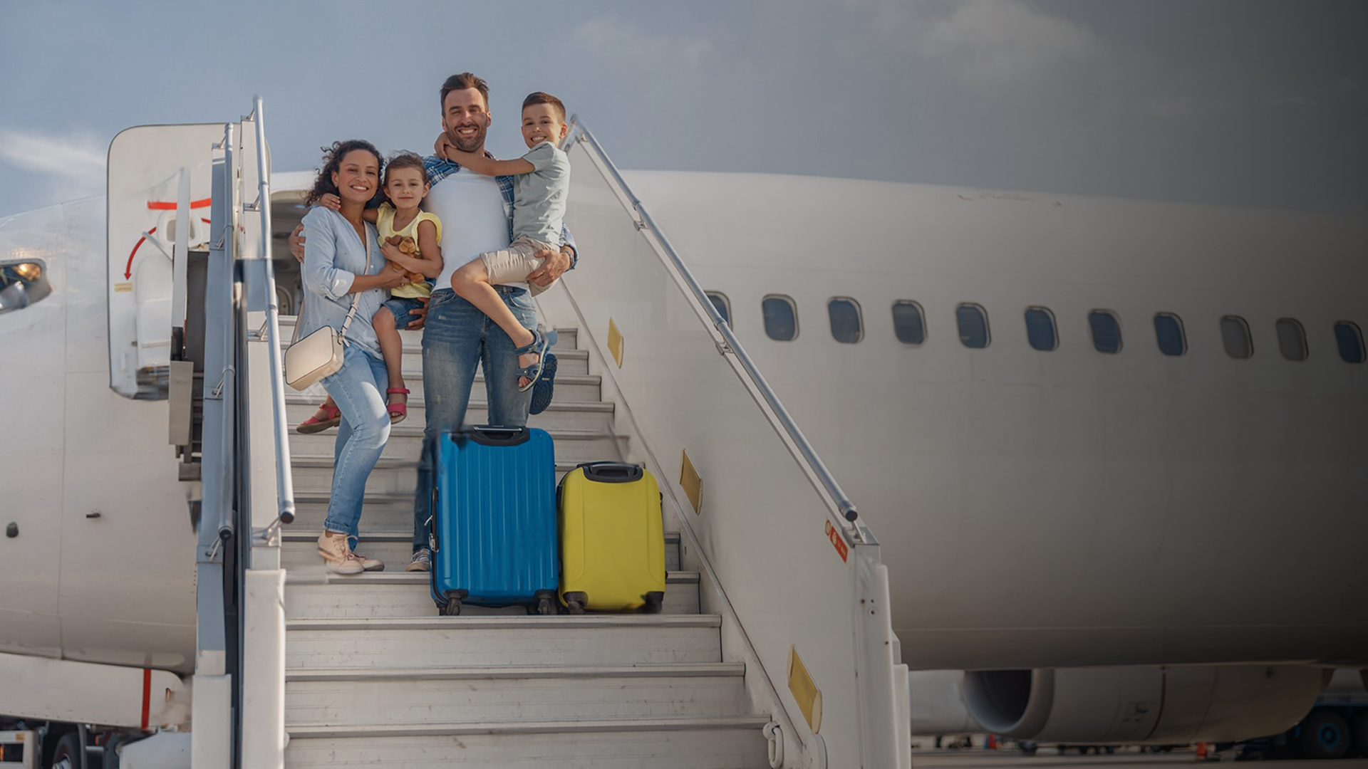 A family is boarding an airplane with their luggage.