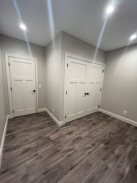A bedroom with hardwood floors and white doors.