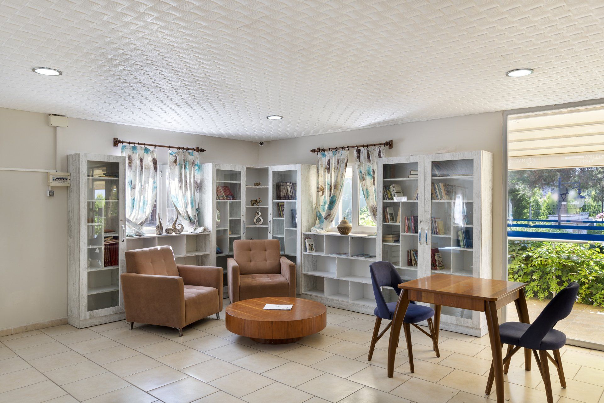 Ein Wohnzimmer mit Tisch, Stühlen und Regalen