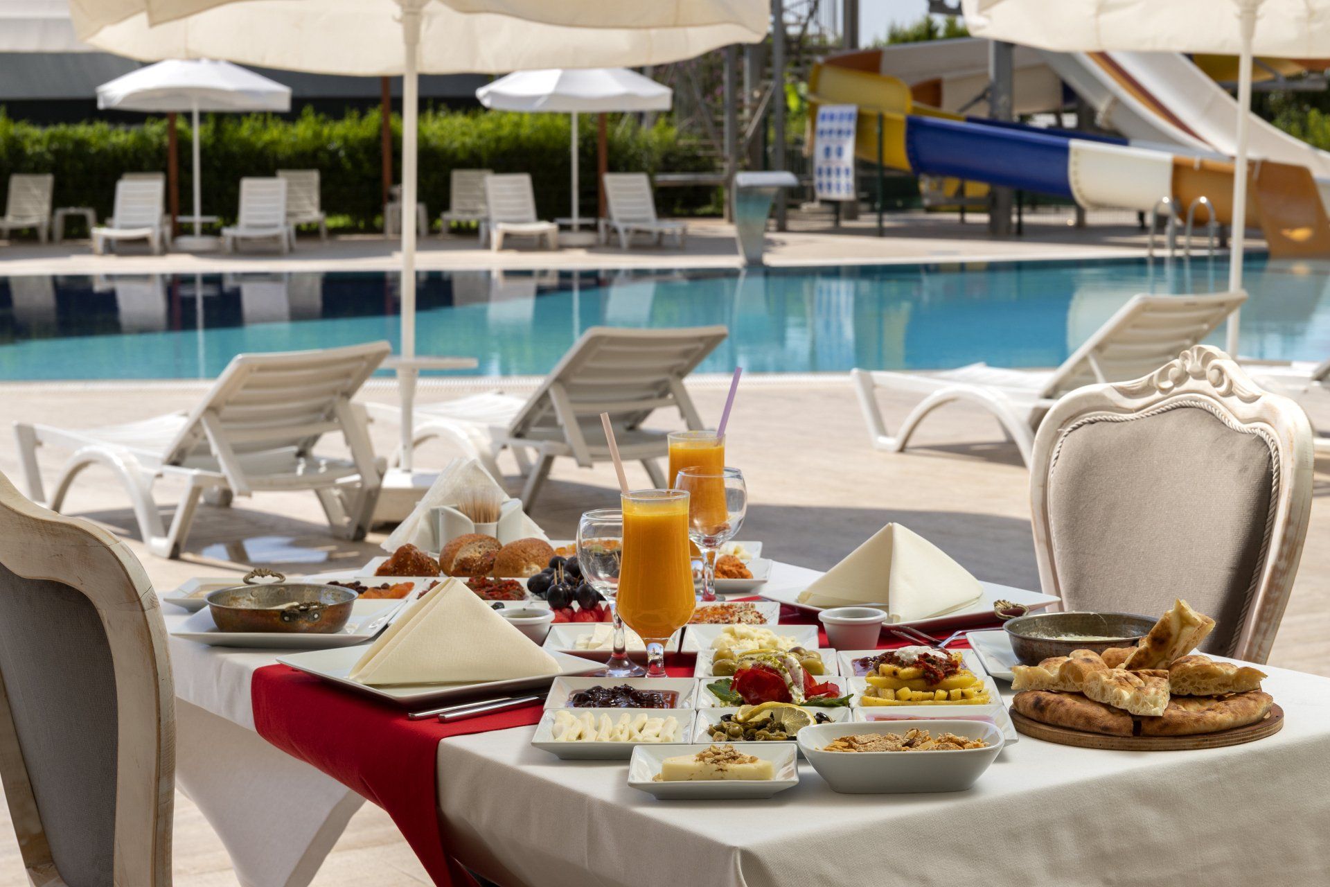 Ein Tisch mit viel Essen darauf vor einem Pool.