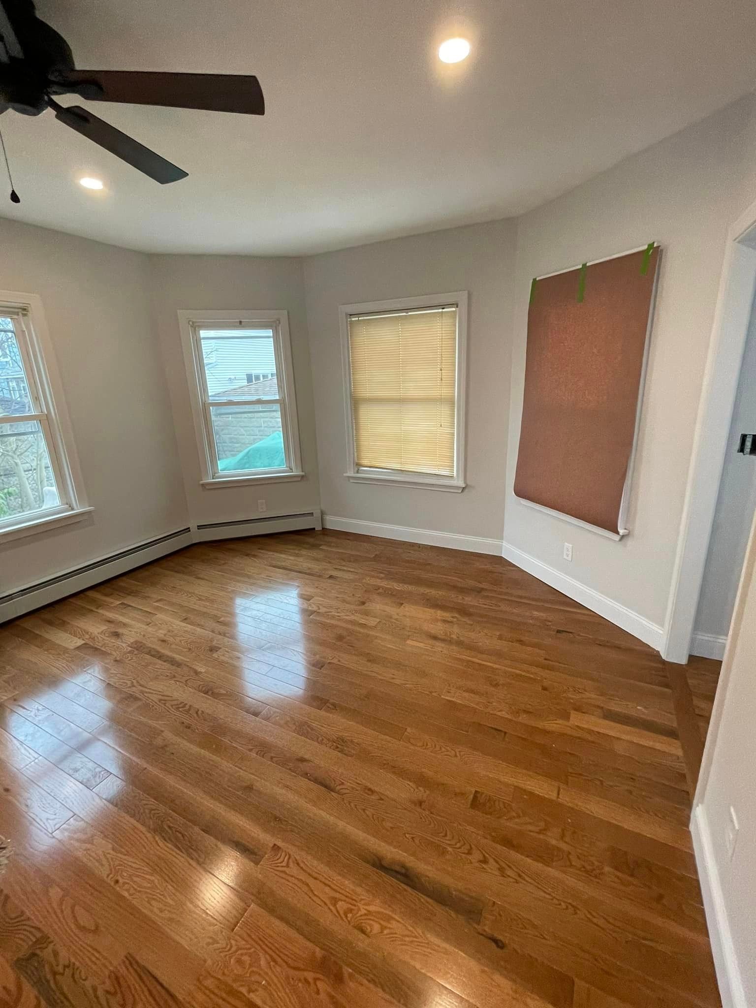 An empty living room with hardwood floors and a ceiling fan.
