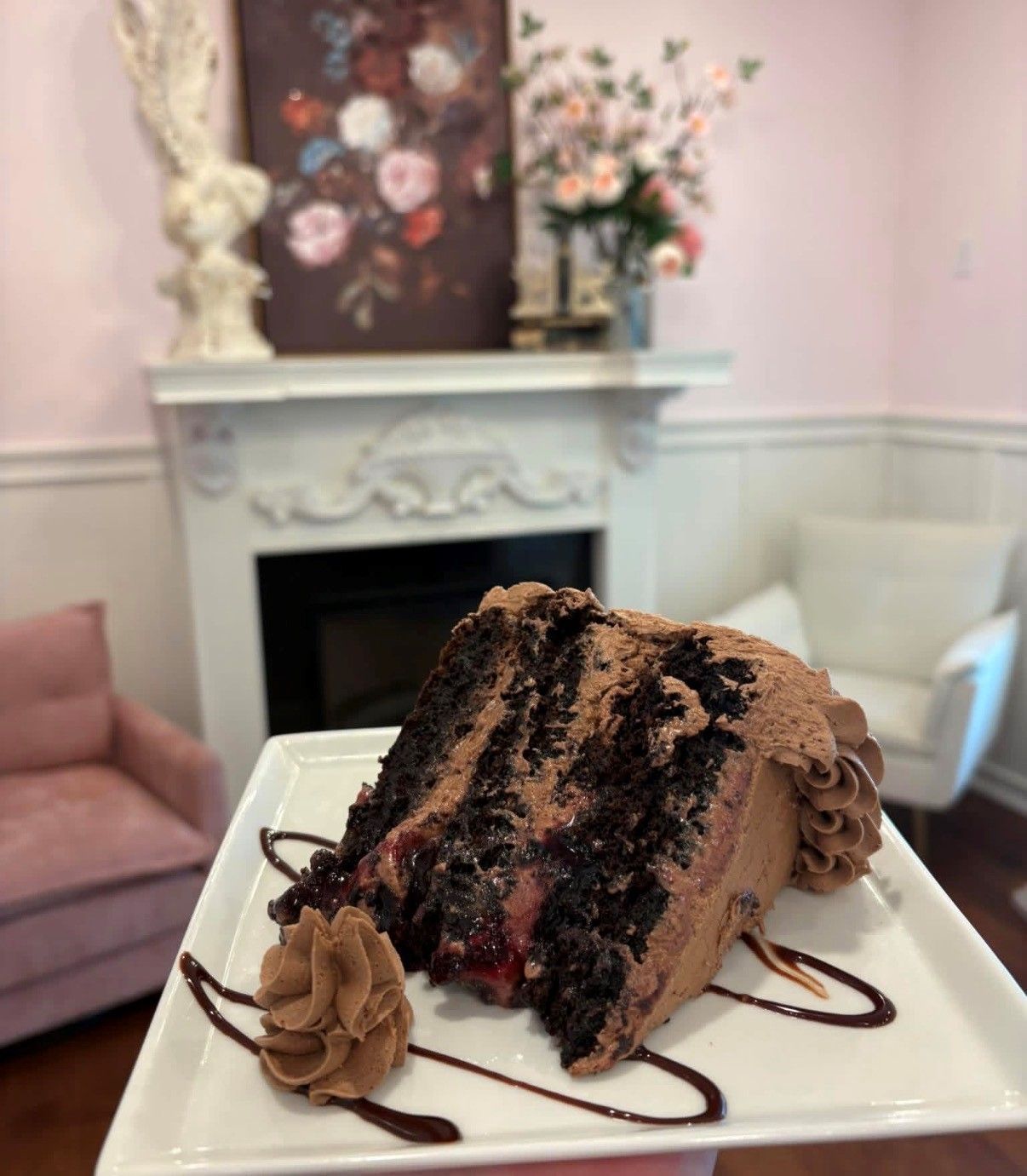 Slice of chocolate cake on a plate in a pastel lounge with fireplace and floral decor