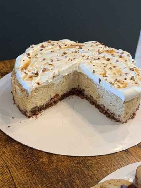 Partially sliced white frosted cake on a white platter with sprinkled topping