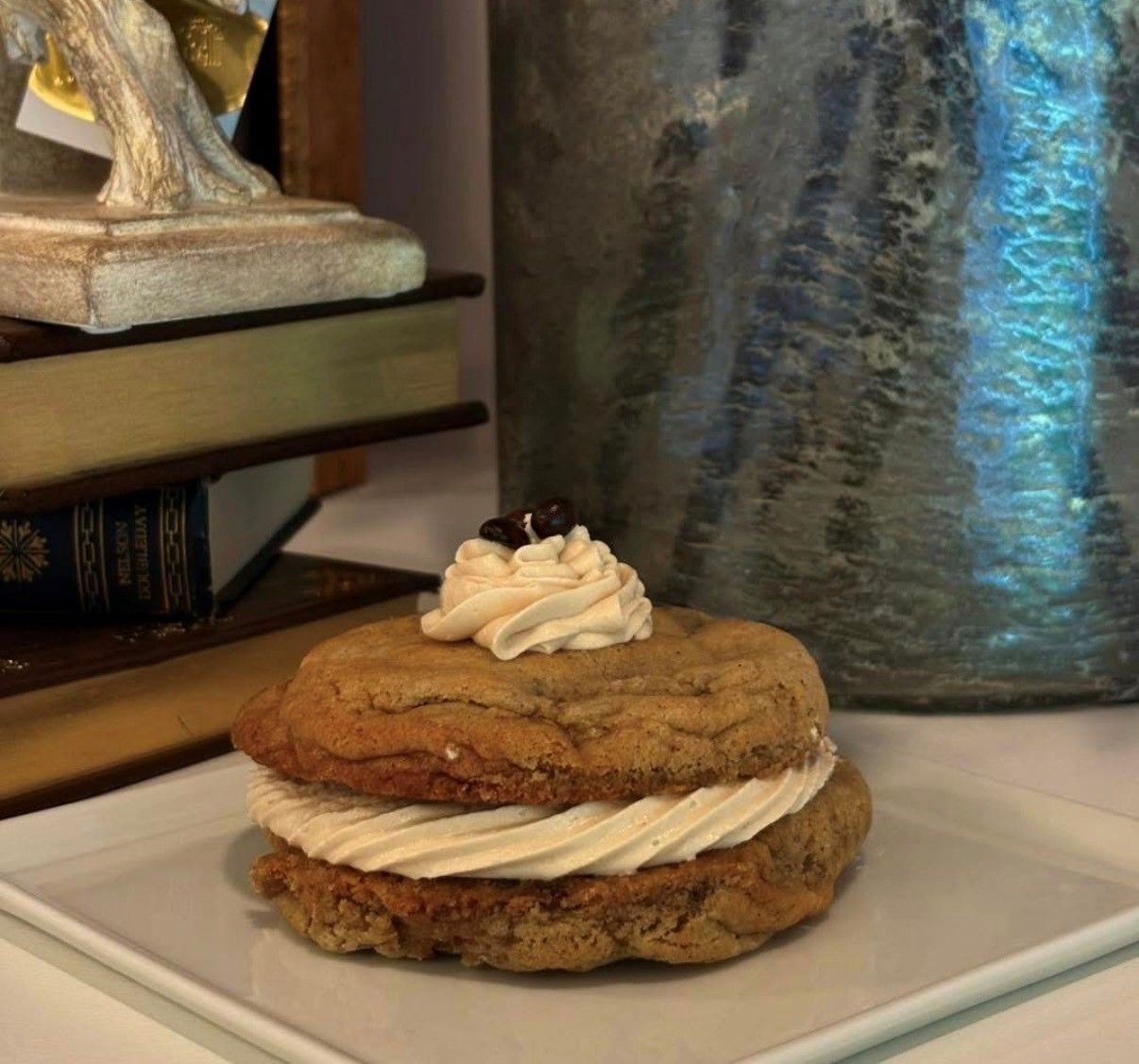 Cookie sandwich dessert with cream filling and whipped topping on a white plate