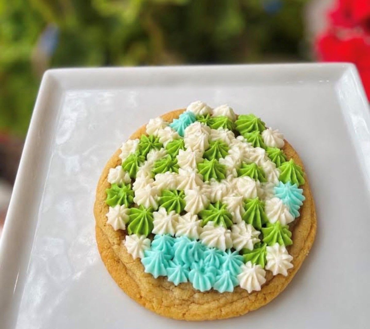 Colorful frosted cookie on a white plate with green, white, and blue icing stars