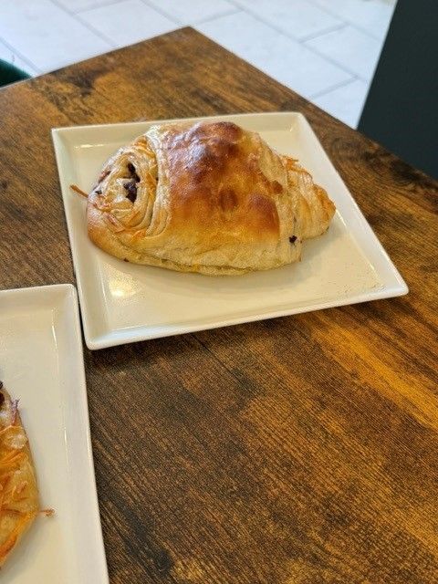Golden-brown pastry on a white square plate on a wooden table